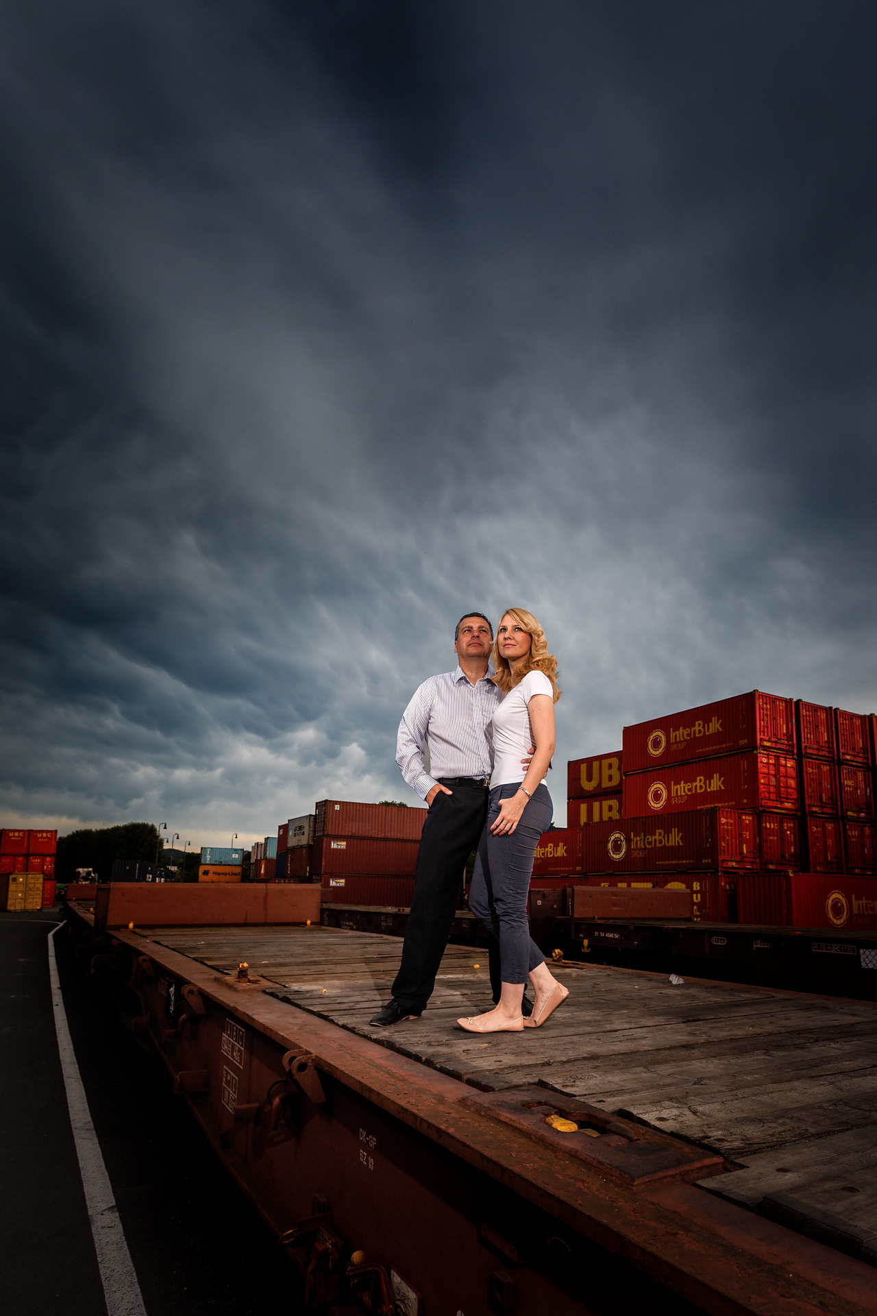 Snoubenci na vagóně na pozadí červených kontejnerů.